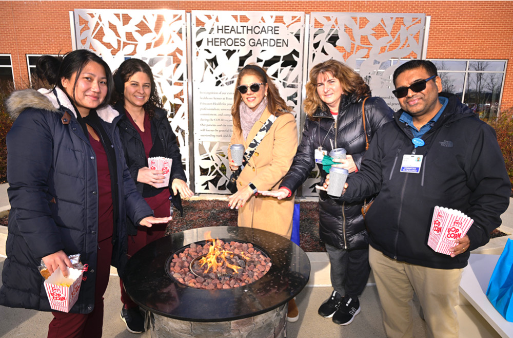 Princeton Health staffers warming by the fire at 2022 Winter Wonderland 
